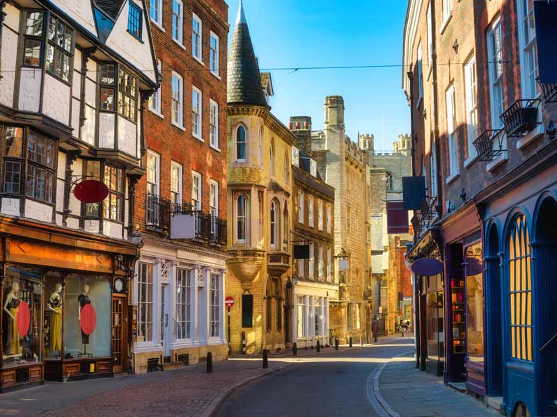 Photo looking down a quiet street full of shops in Cambridge city centre.